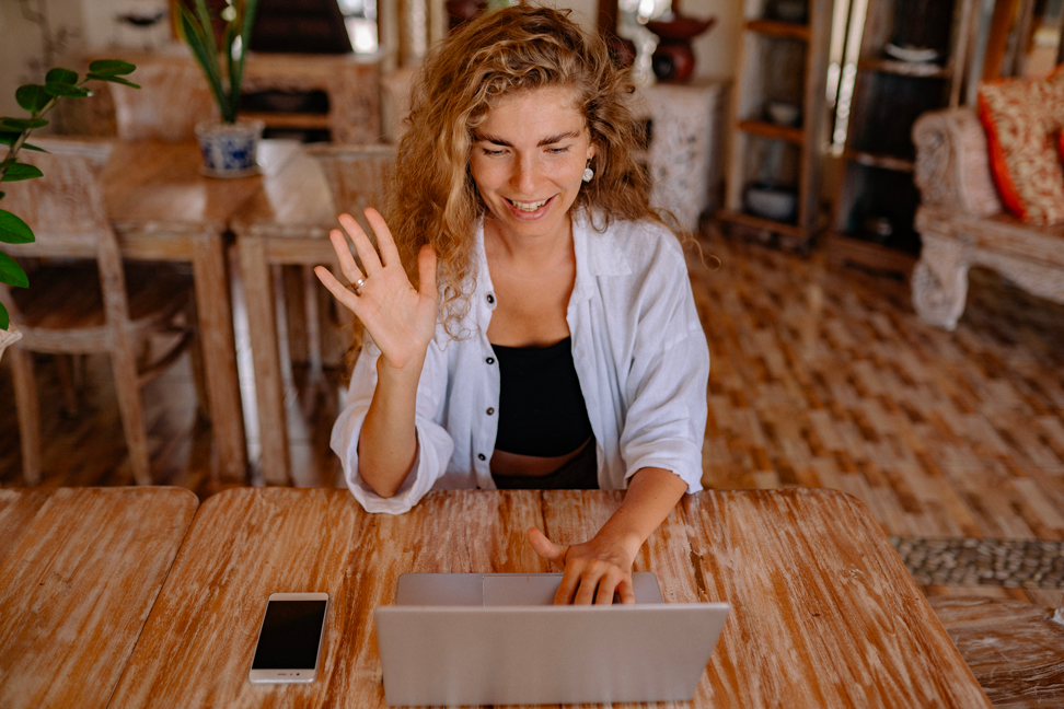 Une femme lève la main devant son ordinateur portable
