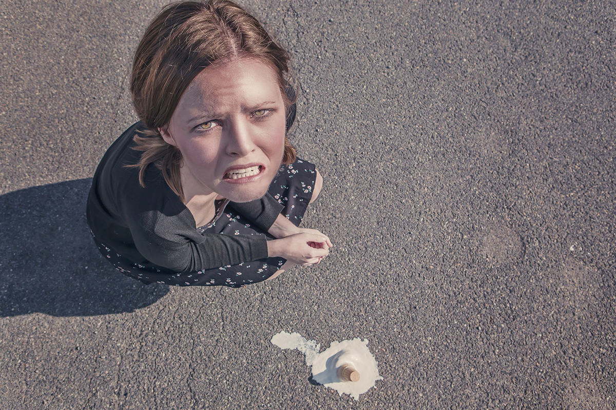 Une femme avec une expression de dégoût sur le visage est accroupie à côté d'un cornet de glace écrasé sur le sol