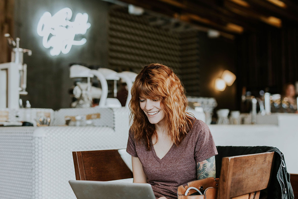 Une femme tatouée souriant devant son ordinateur portable