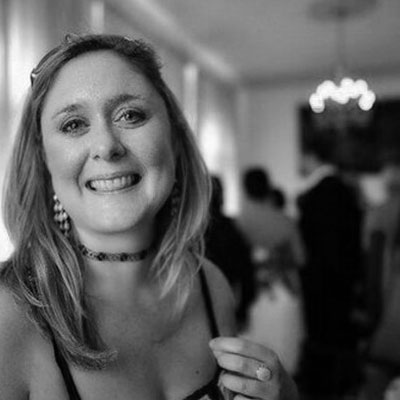 Une femme portant un collier et une bague sourit en regardant droit devant elle