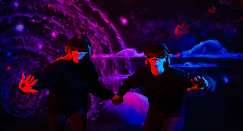 Deux personnes portent un casque en réalité virtuelle et se tiennent la main