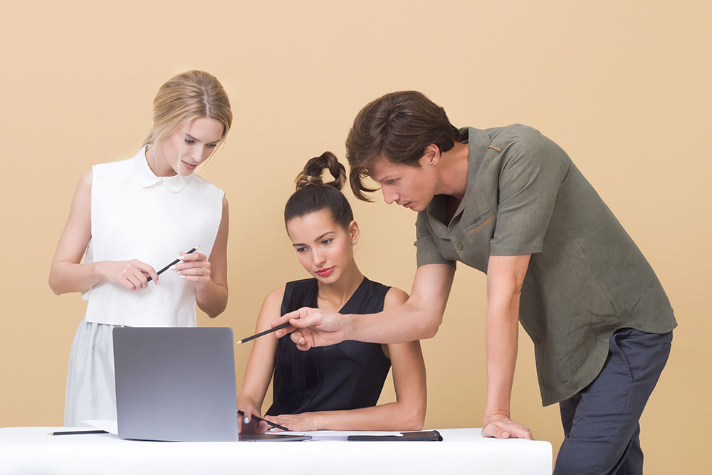 Trois personnes parlent en regardant un ordinateur portable