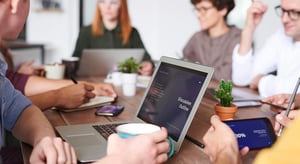 Réunion d’équipe autour d’une table avec ordinateurs, smartphones et café. - Article de blog Eventdrive