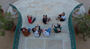Groupe de collaborateurs assis en cercle sur des marches en pierre lors d’un team building en extérieur, vus de haut. - Article de blog Eventdrive