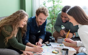 Quatre collègues réunis autour d'une table, penchés sur une carte et des notes, souriant pendant la planification d'un team building - Article de blog Eventdrive