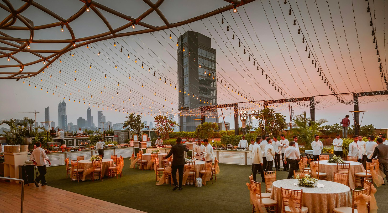 Rooftop événementiel au coucher du soleil, décoré de guirlandes lumineuses, prêt à accueillir un événement d’entreprise avec 2000 invités en extérieur - Article de blog Eventdrive