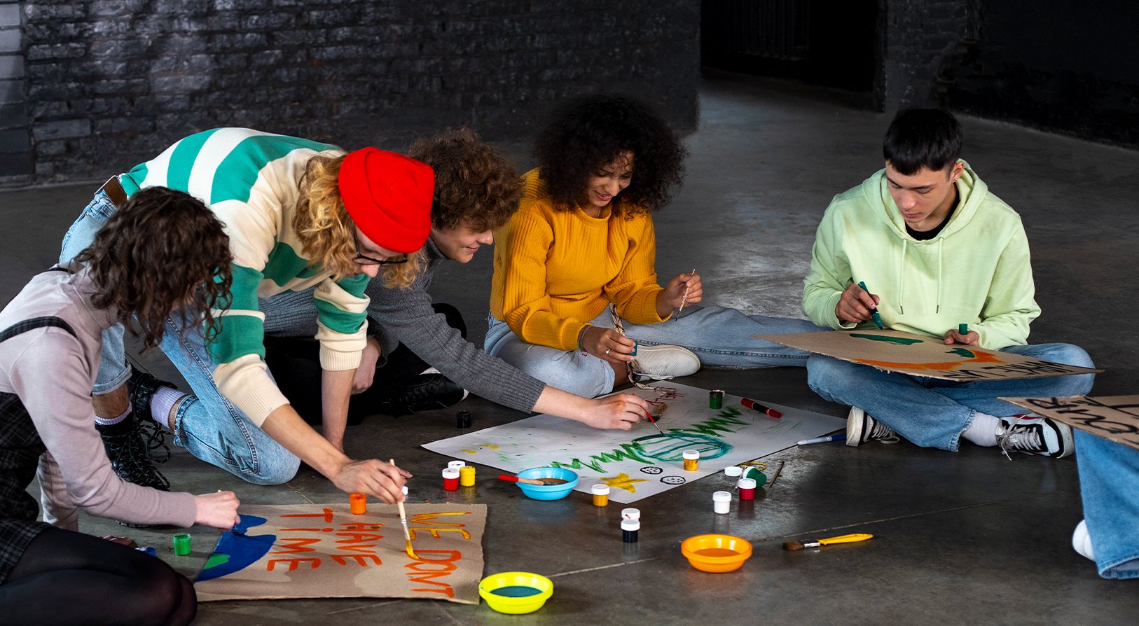 Groupe de jeunes participants assis au sol, en pleine activité artistique collaborative lors d’un atelier créatif pendant un séminaire d’entreprise. - Article de blog Eventdrive