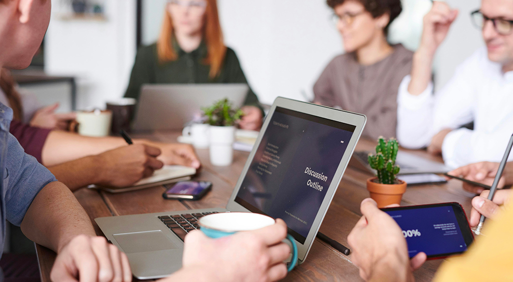 Réunion d’équipe autour d’une table avec ordinateurs, smartphones et café. - Article de blog Eventdrive