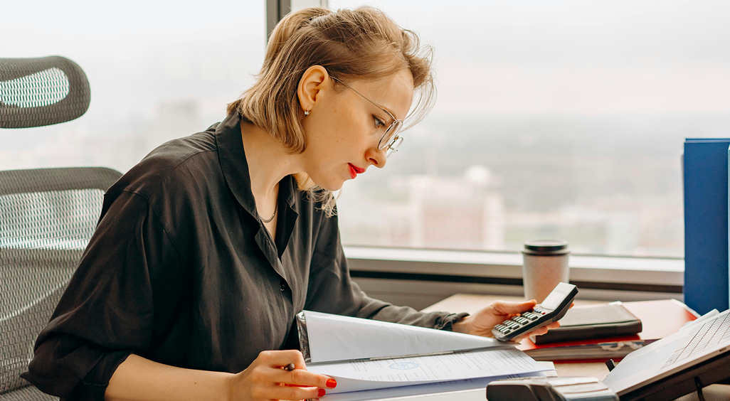 Responsable financière analysant un budget avec une calculatrice. Image qui illustre l’enjeu des coûts cachés dans la gestion événementielle en entreprise. - Article de blog Eventdrive